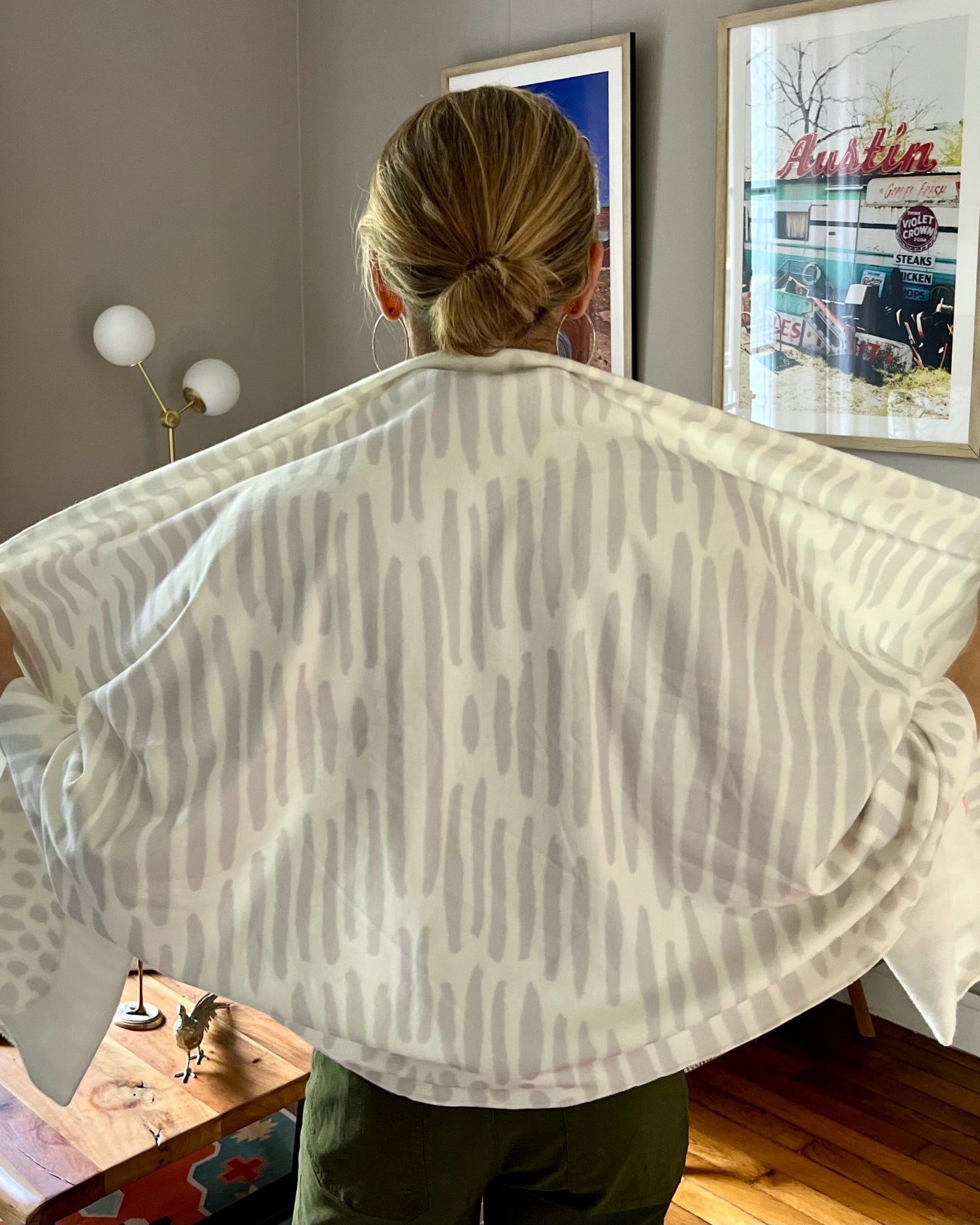 Woman wearing a white and light gray owl print wrap over green pants in a living room