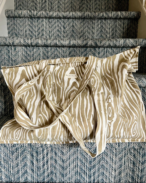 A beige and white faux bois pattern tote bag placed on a staircase.