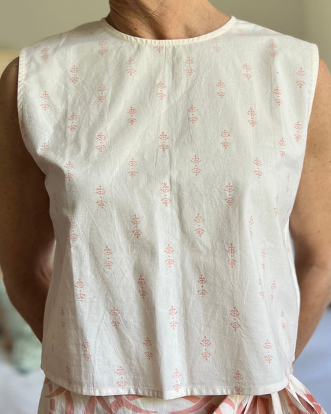 A person wearing a pale peach sleeveless boxy top with a crew neck, paired with a long wrap skirt