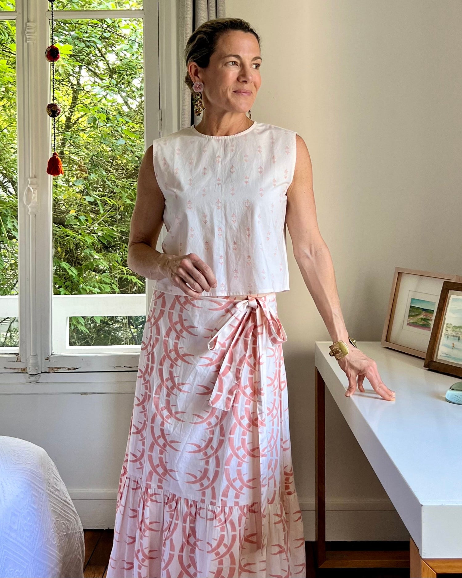 A person wearing a pale peach sleeveless boxy top with a crew neck, paired with a long wrap skirt
