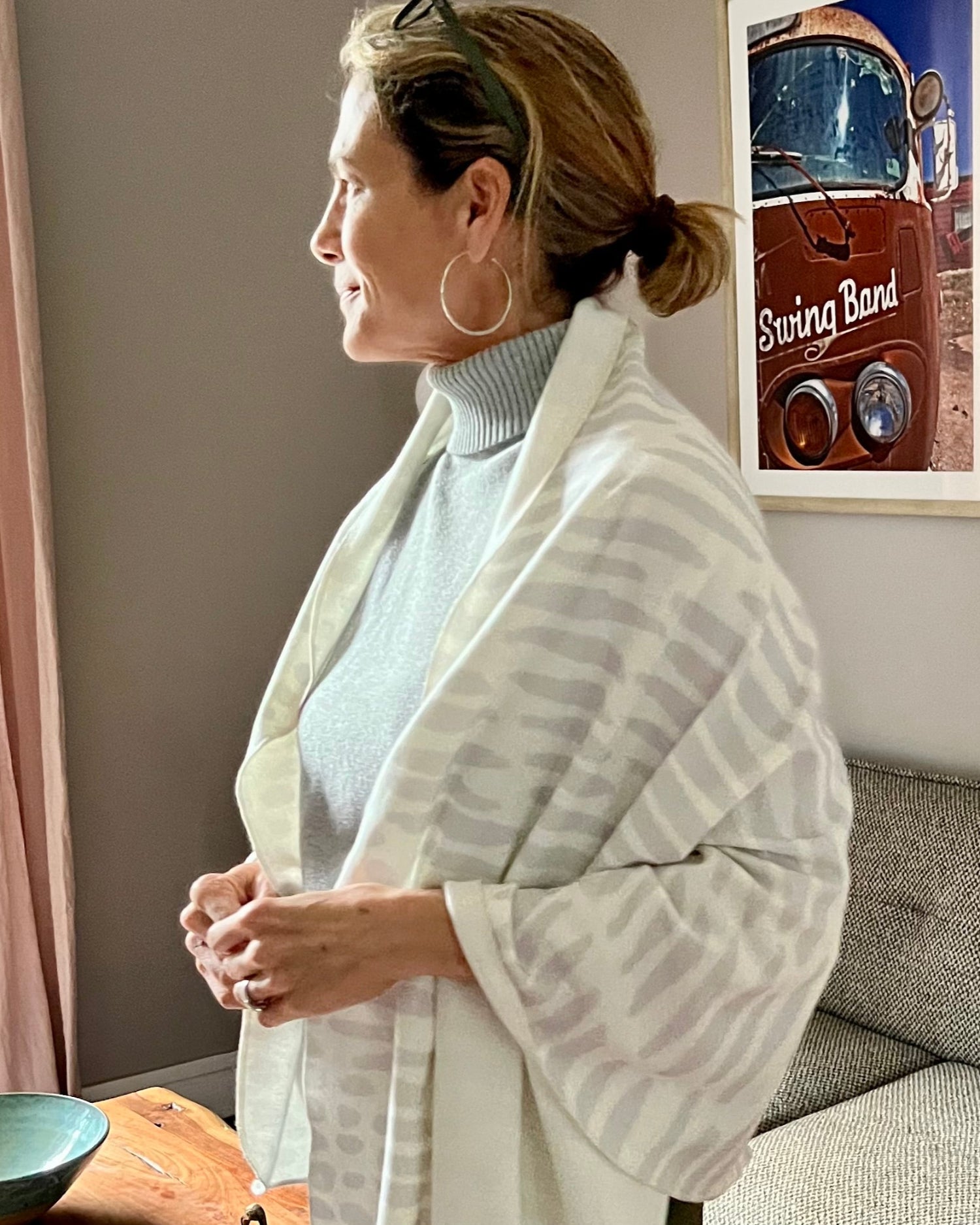 A person standing by a window, wearing a white cozy wrap with a light gray owl print