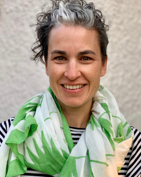 Person wearing a green and white hand block-printed sarong / grand scarf with a neutral background