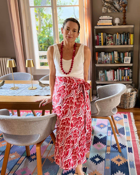 Woman wearing beautiful red and purple block-printed wrap skirt standing in a chic dining room