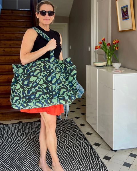 A woman holding a green and black block printed tote bag with an animal print pattern.