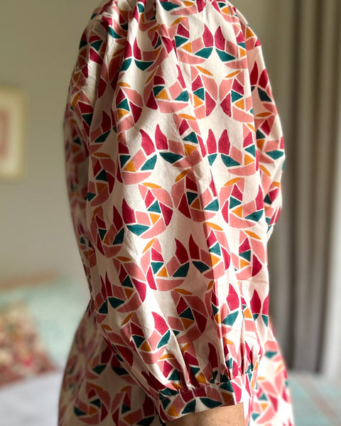 Side view of a woman in a multi-colored block printed puff sleeve dress 