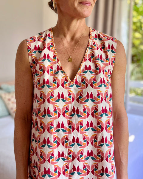 A person wearing a sleeveless, trapeze-shaped summer dress with a confetti mollusk print