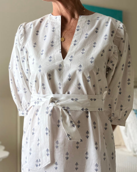 A woman wearing a white puff sleeve dress with blue print