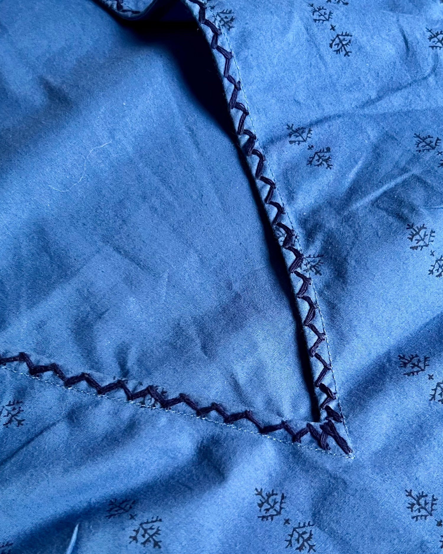 Close-up of deep v-neck and hand-embroidery on sleeveless, trapeze-shaped royal blue mini dress