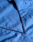Close-up of deep v-neck and hand-embroidery on sleeveless, trapeze-shaped royal blue mini dress