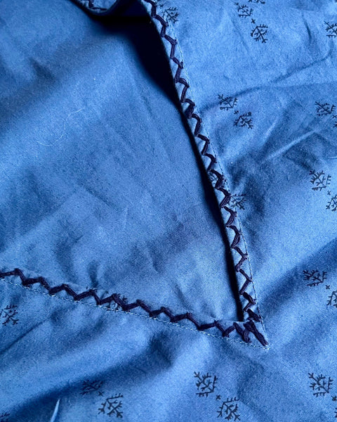 Close-up of deep v-neck and hand-embroidery on sleeveless, trapeze-shaped royal blue mini dress