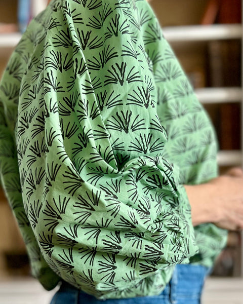 Sideview of woman wearing a pine green colored blouse with a blackbuck animal pattern and puffy sleeves