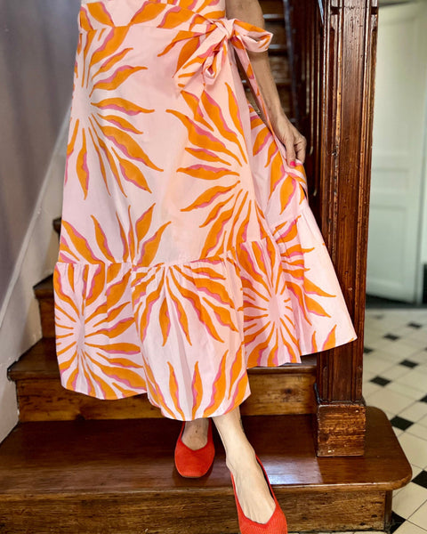 Woman wearing pink and orange wrap skirt with bow and ruffle on stairs