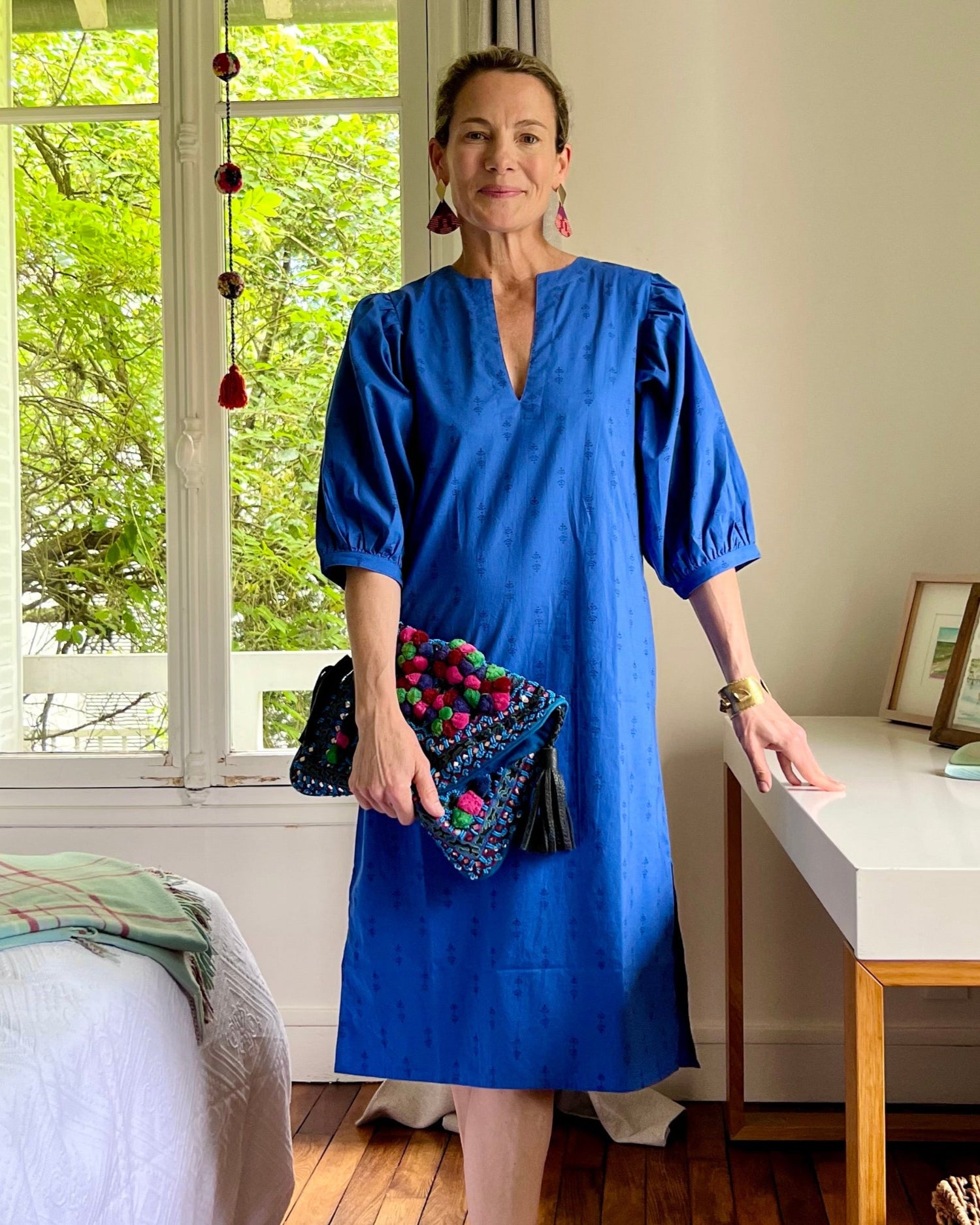 A woman standing in a room wearing a royal blue dress with puff sleeves and a V-neck