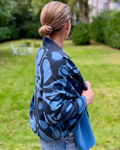 A person wearing a navy blue and black scarf featuring a wild dog print wrapped around the body