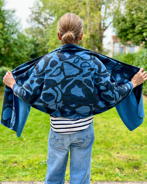 A person wearing a striped shirt with a navy blue and black scarf featuring a wild dog print wrapped around the body