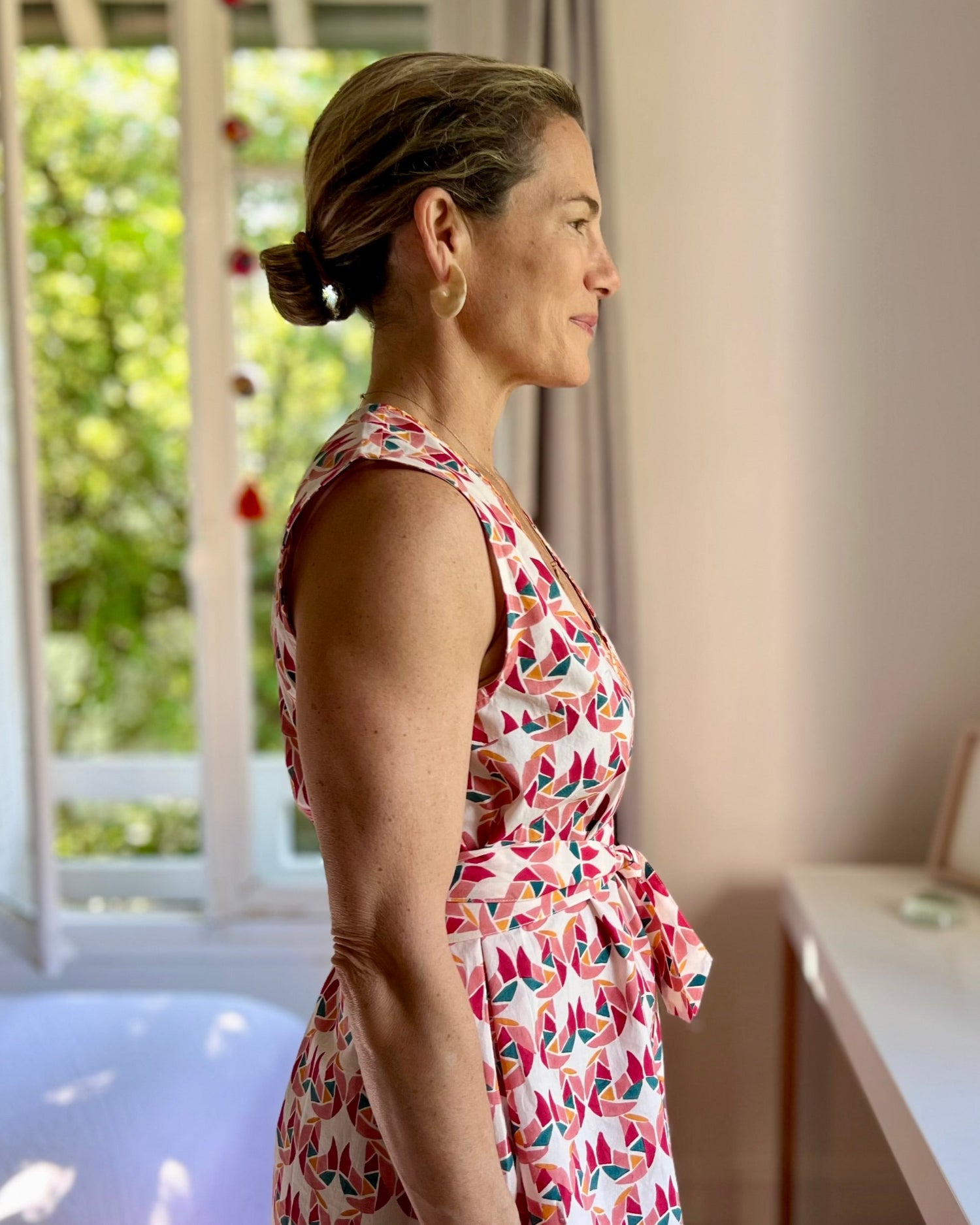 Side view of a person wearing a sleeveless, trapeze-shaped summer dress with a confetti mollusk print 