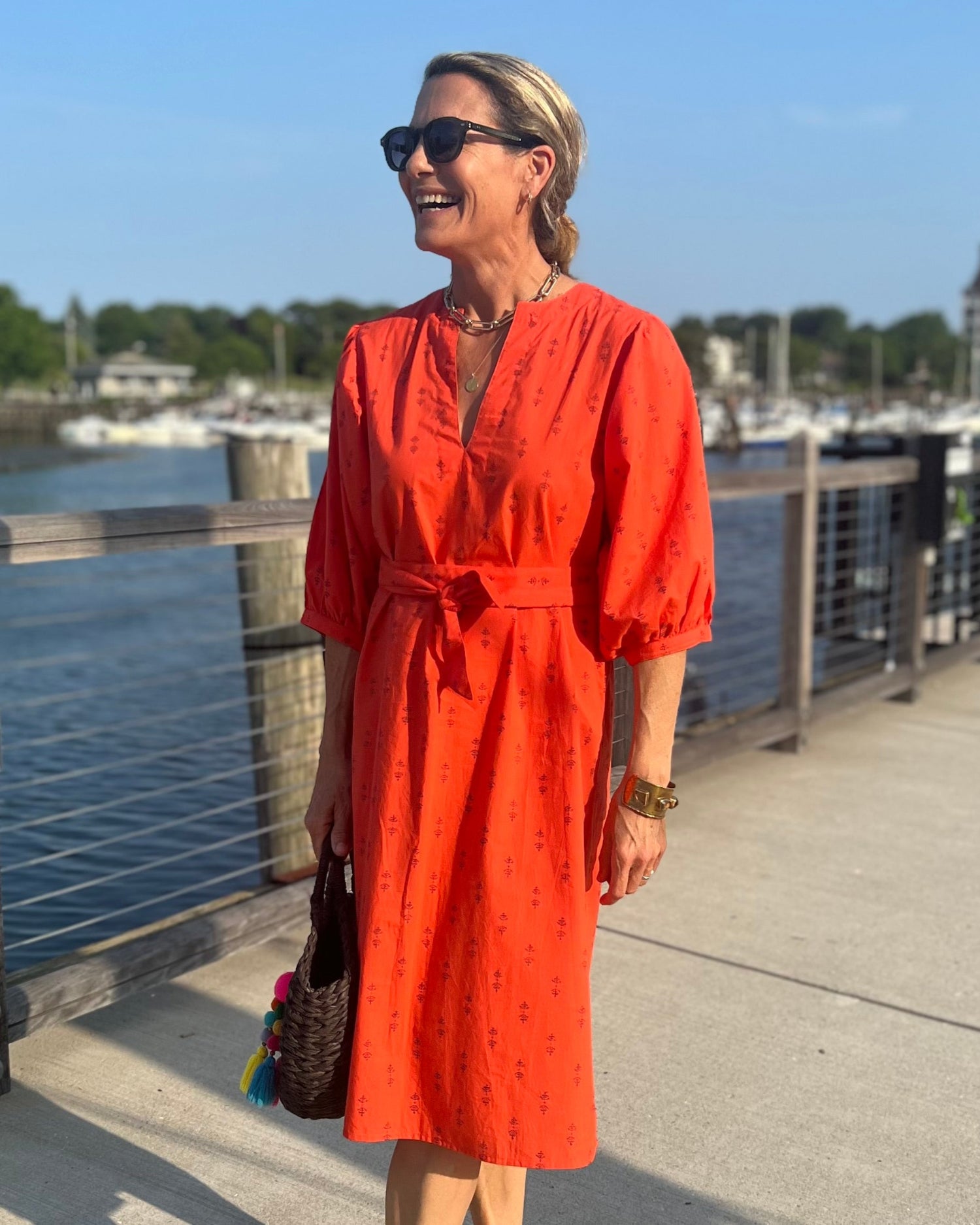 A person wearing a red dress with puff sleeves and sash belt next to water
