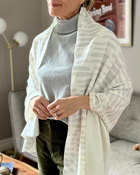 Smiling woman wearing a white and light gray owl print wrap over gray sweater