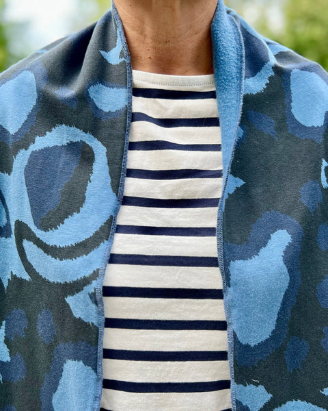 A person wearing a striped shirt with a navy blue and black scarf featuring a wild dog print 