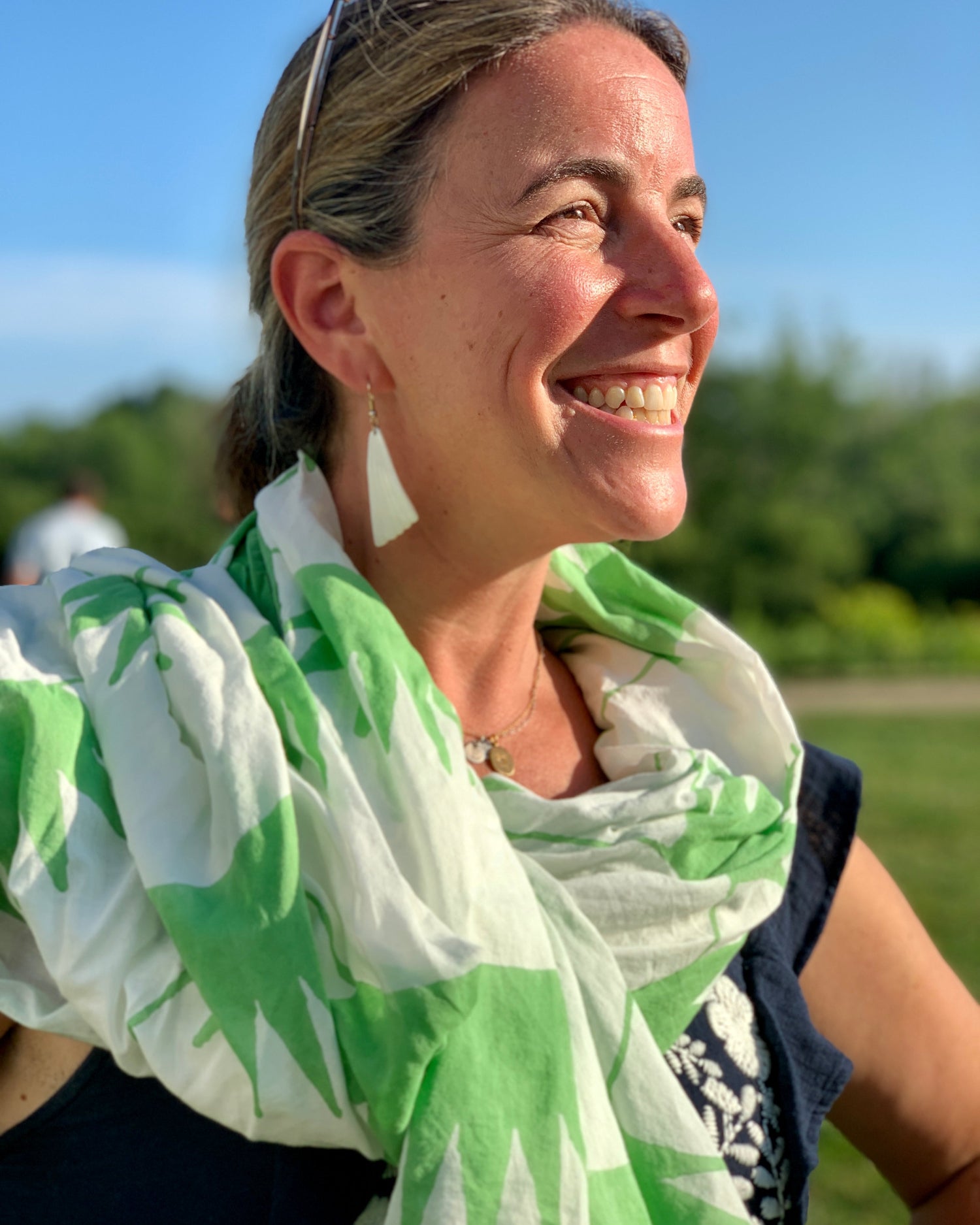 A person wearing a hand block-printed grass green and white sarong / grand scarf smiling in the sun