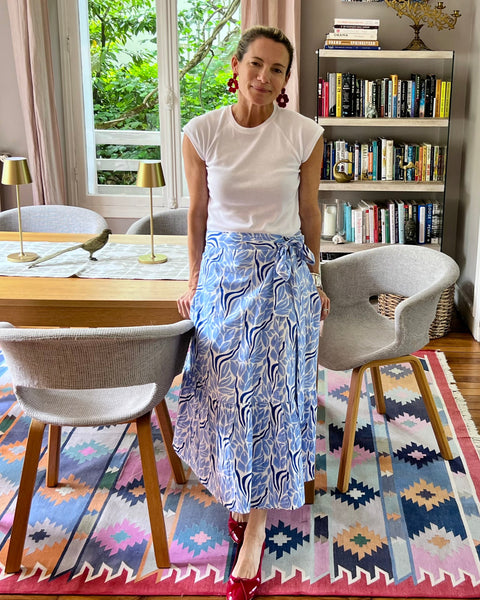 Woman leaning against a dining room table wearing a white top and blue and white hand block-printed wrap skirt 