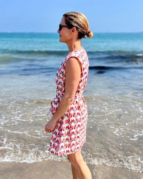 A person wearing a sleeveless, trapeze-shaped summer dress with a confetti mollusk print