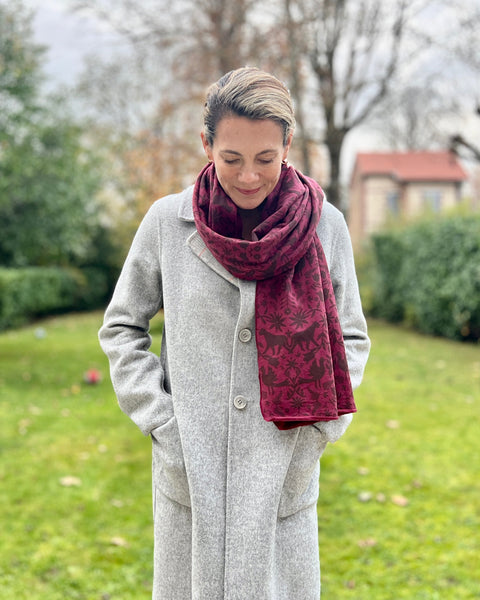 A person with a gray coat wearing a wine-colored cozy wrap with a brown jaguar print.