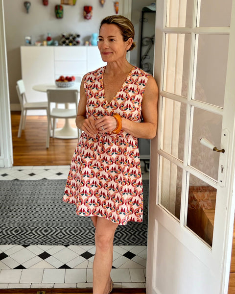 A person wearing a sleeveless, trapeze-shaped summer dress with a confetti mollusk print by french doors