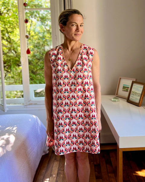 A person wearing a sleeveless, trapeze-shaped summer dress with a confetti mollusk print