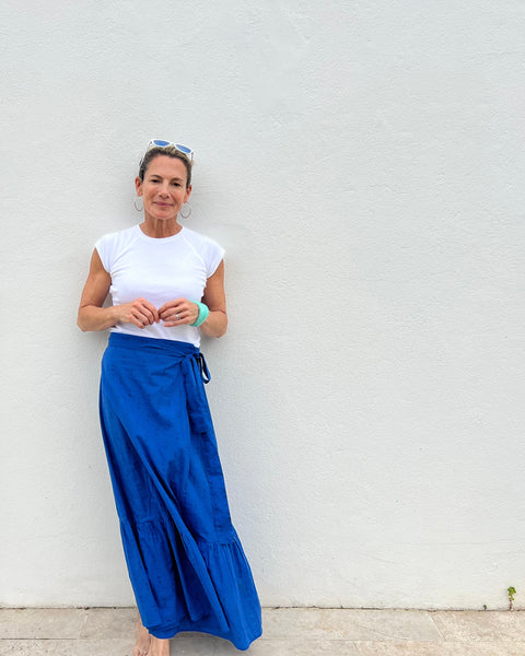 Woman in a royal blue hand block-printed maxi skirt standing in front of a white building
