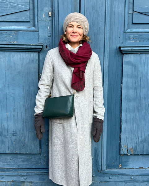 A person with a gray coat wearing a wine-colored cozy wrap with a brown jaguar print.