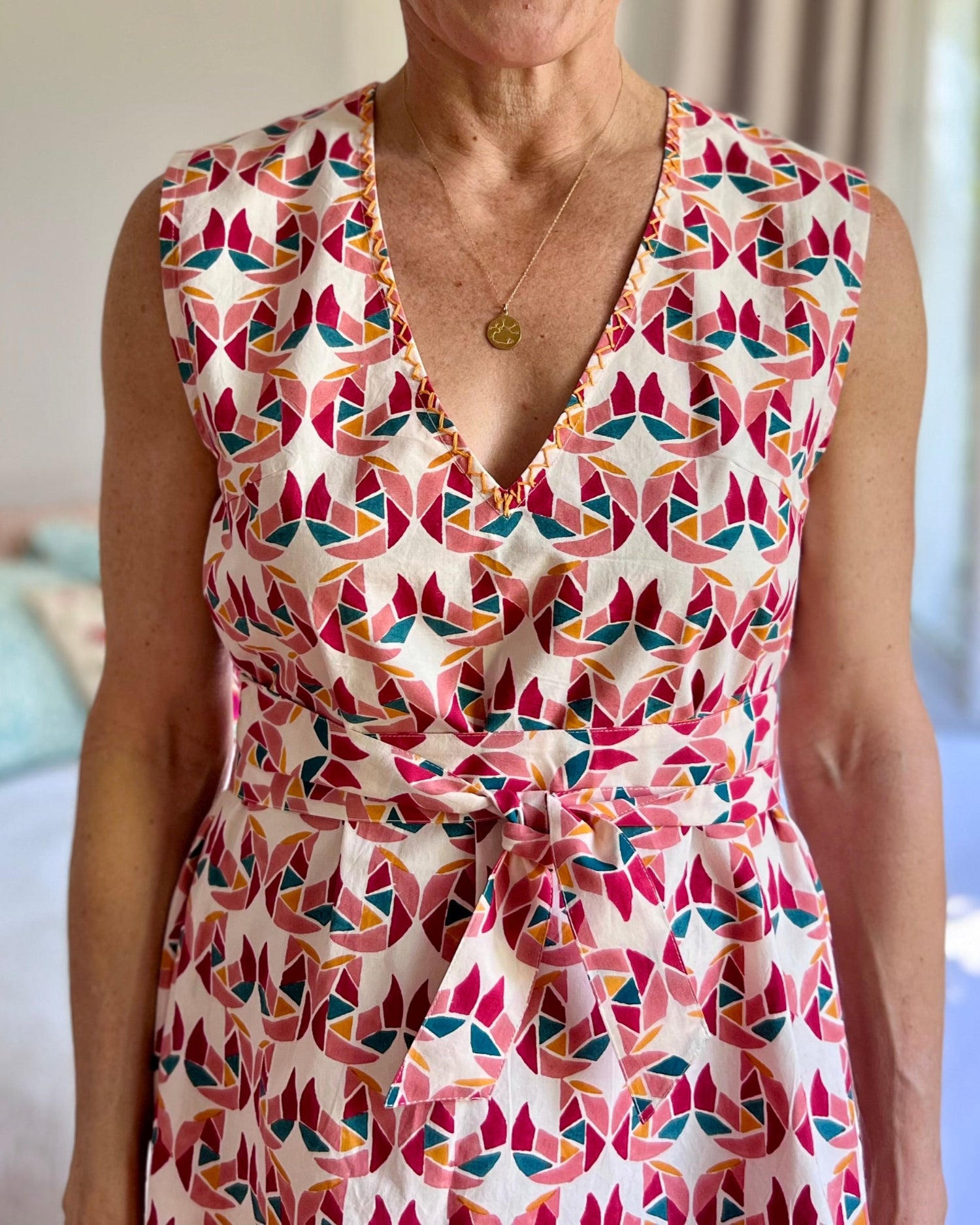 A person wearing a sleeveless, trapeze-shaped summer dress with a confetti mollusk print