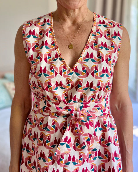 A person wearing a sleeveless, trapeze-shaped summer dress with a confetti mollusk print