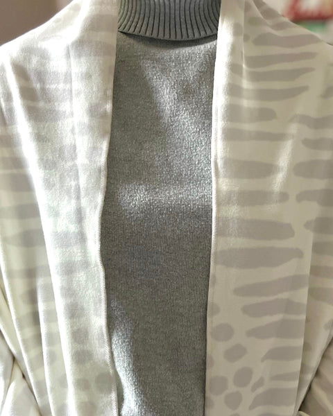 Woman wearing a white and light gray owl print wrap over gray sweater
