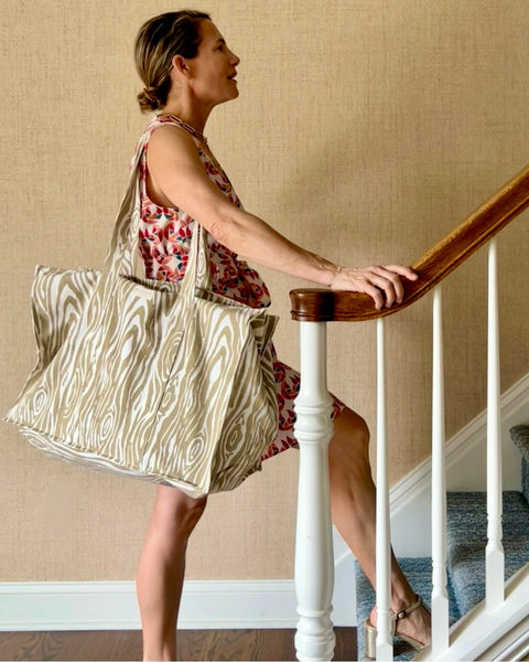 Woman standing at staircase with a beige and white faux bois pattern tote bag.