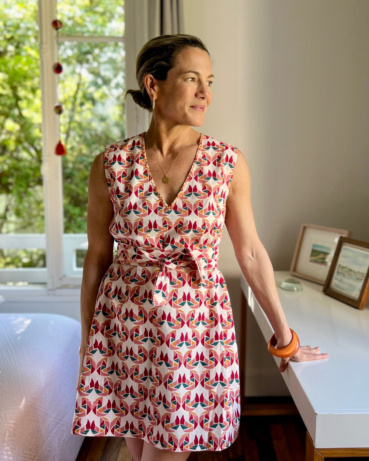 A person wearing a sleeveless, trapeze-shaped summer dress with a confetti mollusk print