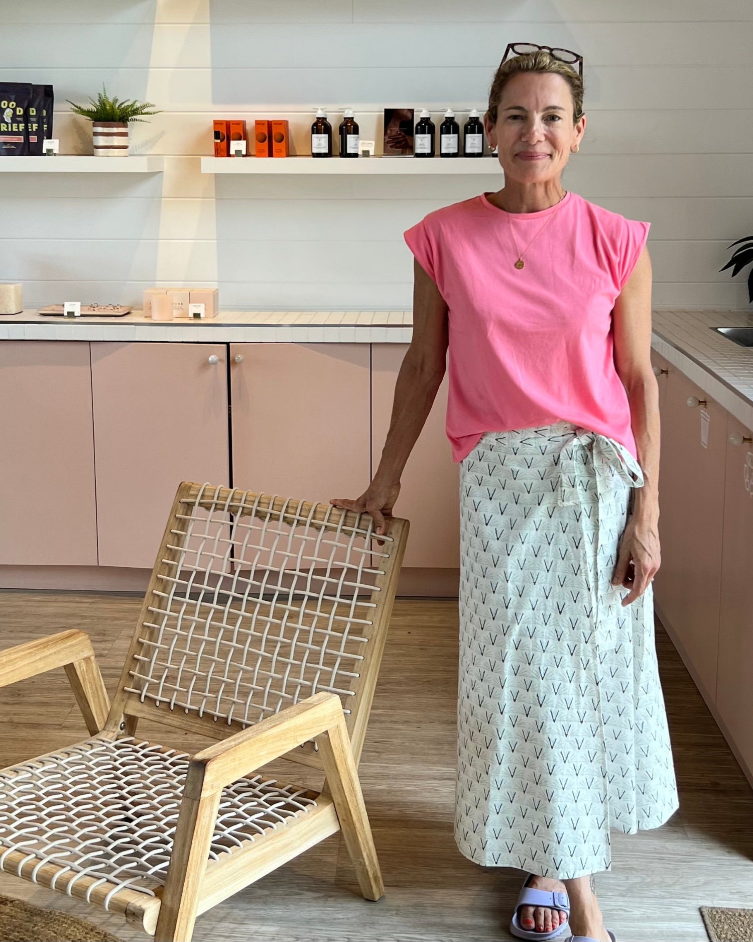 A person wearing an olive green, gray, and blue geometric patterned wrap skirt with a tea length cut and a pink top