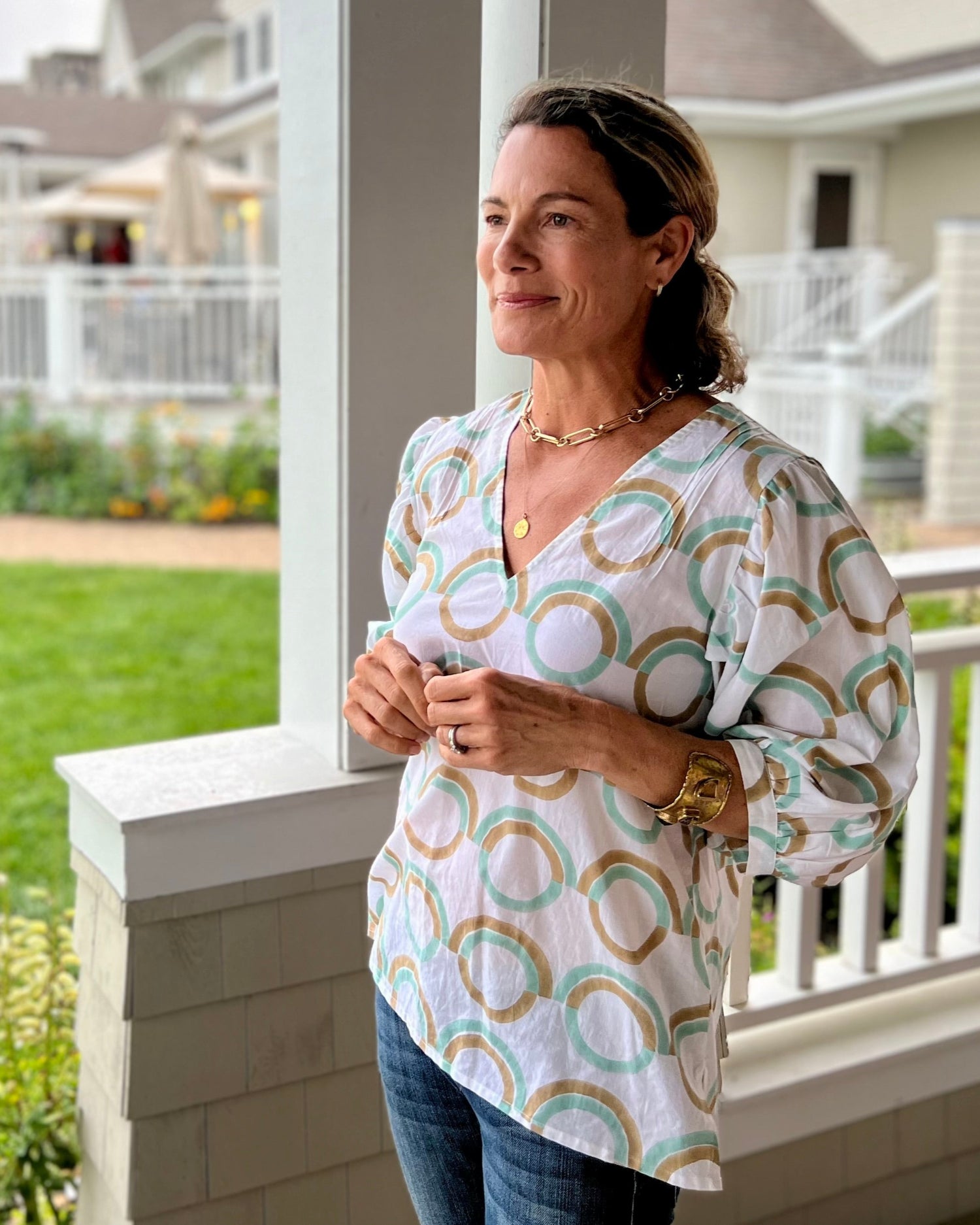 A woman standing outdoors wearing a mint green blouse with puff sleeves, featuring a geometric pattern.