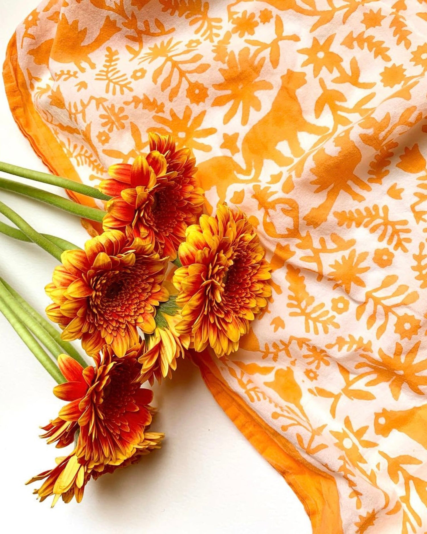 Close-up of orange hand block-printed jaguar sarong / grand scarf with orange gerber daisies