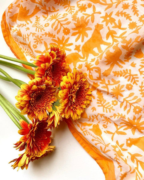 Close-up of orange hand block-printed jaguar sarong / grand scarf with orange gerber daisies