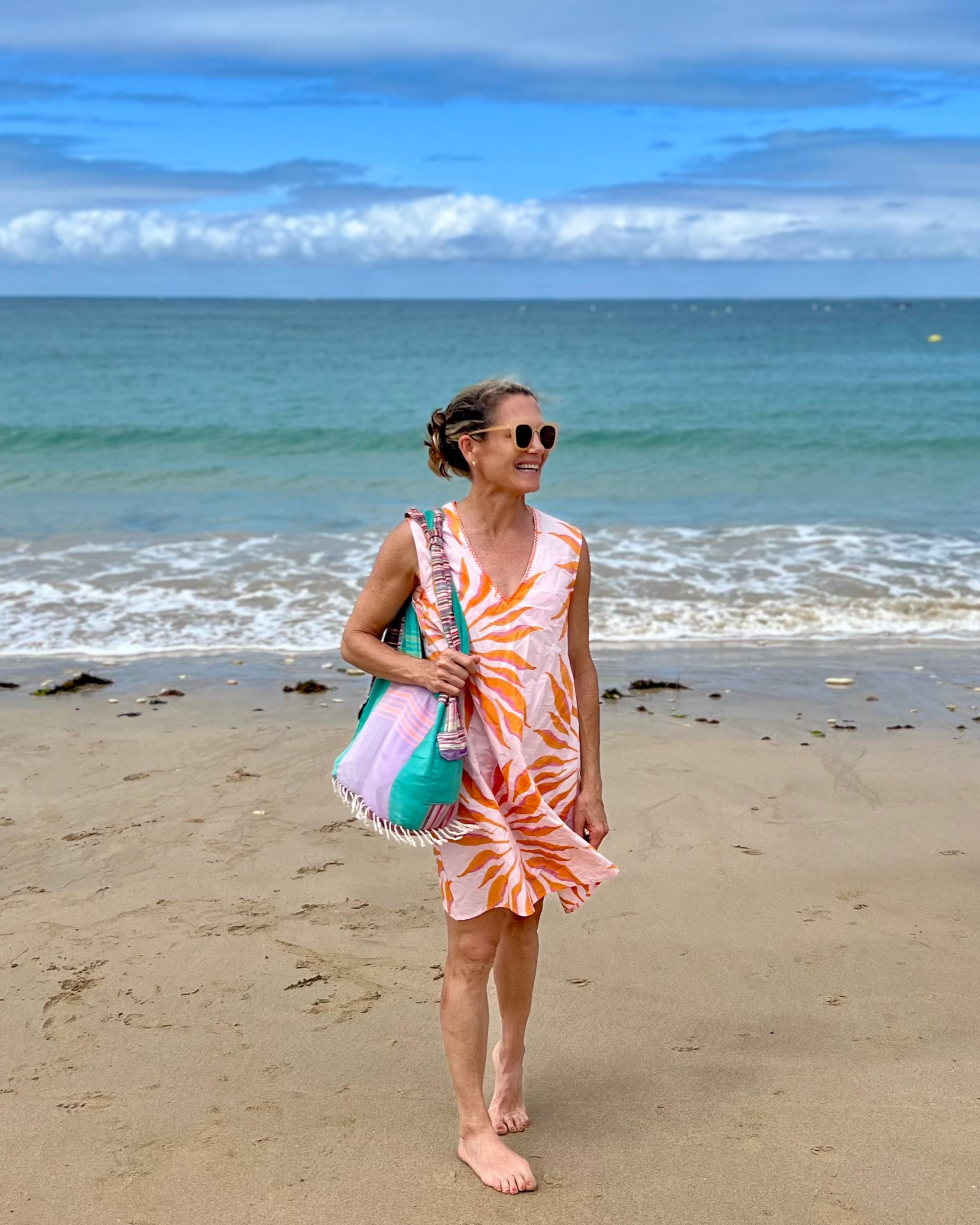 Woman in a pink and orange hand block-printed organic cotton dress on the beach