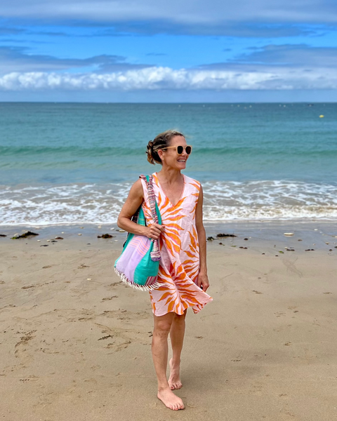 Woman in a pink and orange hand block-printed organic cotton dress on the beach