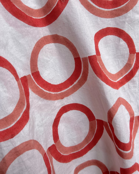 Close-up of white blouse with a coral and pink geometric pattern