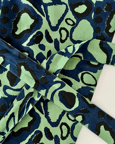 Close-up of green wrap skirt with an animal print in navy blue and black
