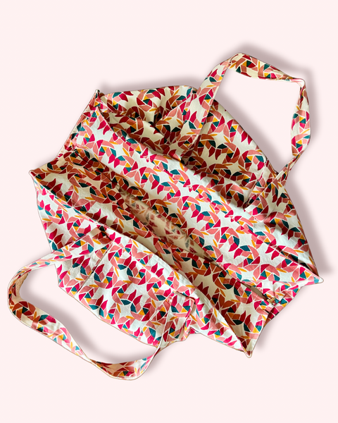 A tote bag with a colorful block-printed pattern featuring mollusks