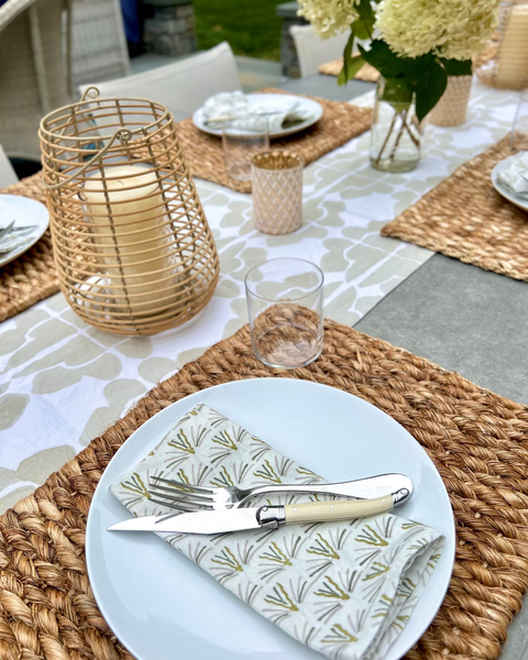 Table setting with plates, cutlery, and decorative elements on a hand block-printed sand / khaki and cream table runner with hand block-printed blackbuck napkins