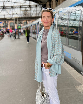 Woman at Paris train station wearing white jeans and light blue cozy wrap/scarf