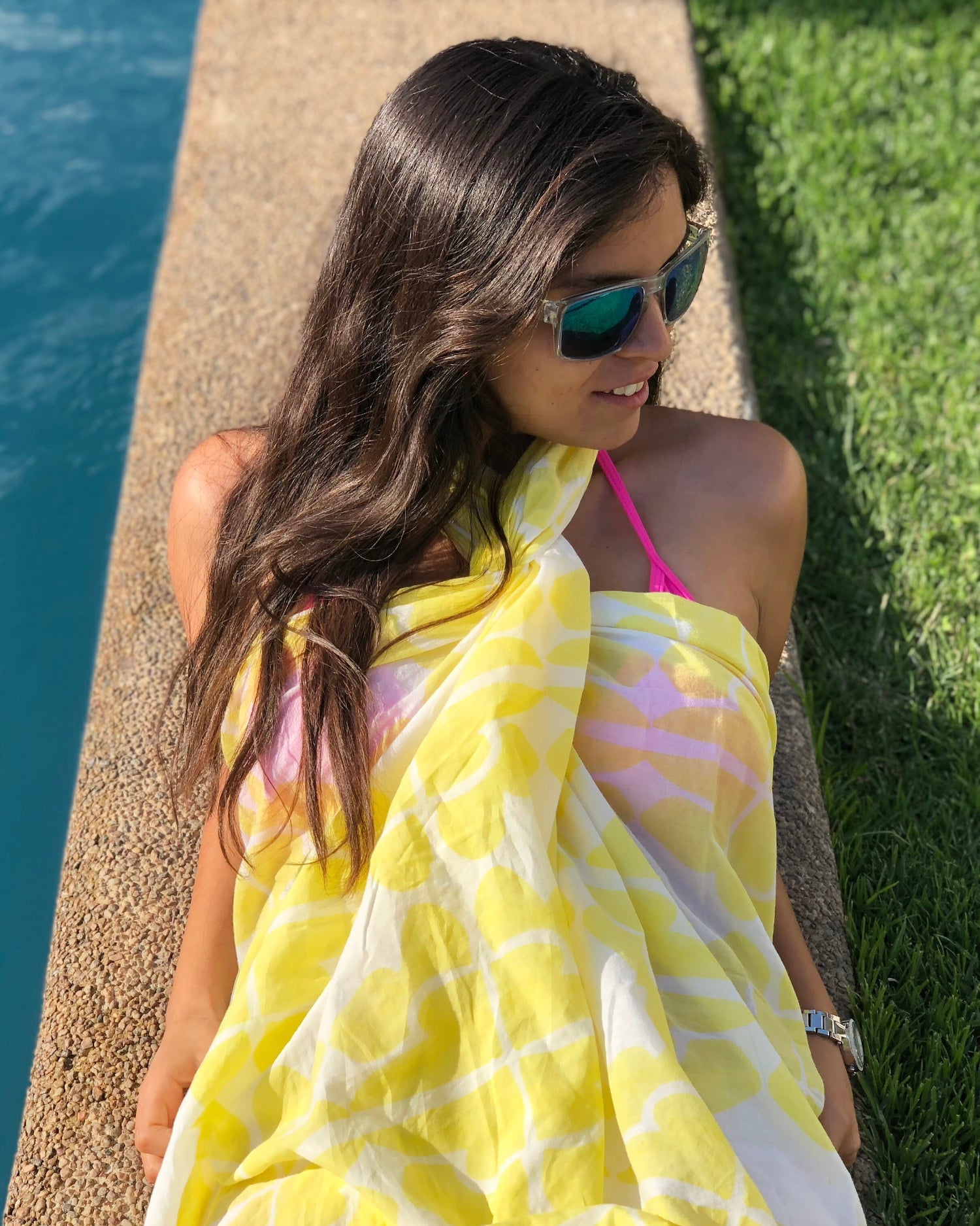 Woman wearing sunglasses and lemon yellow and white hand block-printed sarong / grand scarf by the pool