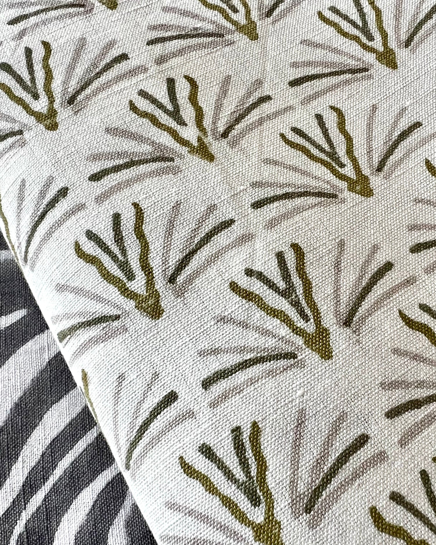 Close-up of cloth napkin with an olive green and gray pattern on a cream background