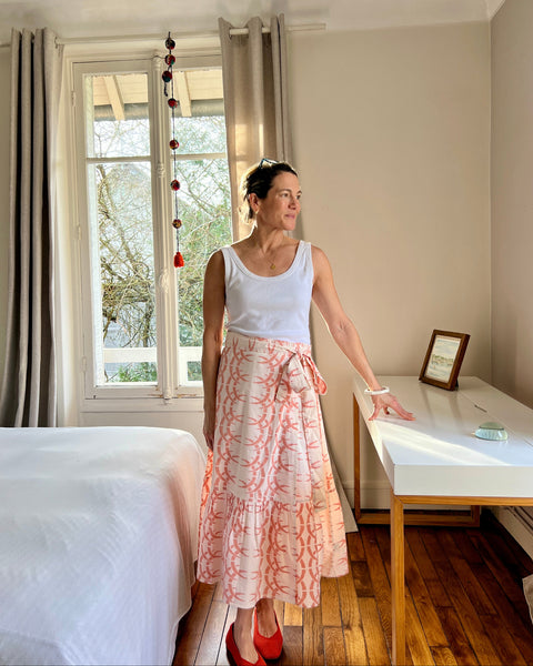 A person wearing a peach-colored wrap skirt with a rhino and horn pattern, paired with a white top.